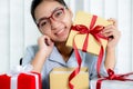 Young Asian woman in a blue shirt opening a golden gift box tied with a red ribbon present for the festival of giving special Royalty Free Stock Photo