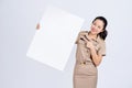 Young asian woman in brown uniform work clothes, She showing and holding blank white billboard Royalty Free Stock Photo