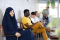 Young asian woman in burqa together with other people of different nationality waiting in office