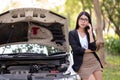 A young Asian woman is calling her service technician to fix a broken car on the side of the road Royalty Free Stock Photo