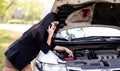 A young Asian woman is calling her service technician to fix a broken car on the side of the road Royalty Free Stock Photo