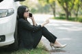 A young Asian woman is calling her service technician to fix a broken car on the side of the road Royalty Free Stock Photo