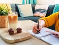 Young Asian woman working from home a hand holding pencil writing agenda note with smartphone, office desk background, Checklist N Royalty Free Stock Photo