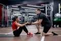 Young asian woman and caucasian man or trainer doing abs with ball with determination together in fitness gym. Royalty Free Stock Photo