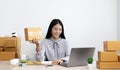 Young Asian woman chatting with a customer on a laptop and displays the product before delivery to confirm the order Royalty Free Stock Photo