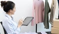 Young Asian women are checking stock of clothes with a tablet to meet customer needs, Counting products before selling, Online clo Royalty Free Stock Photo