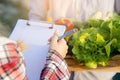 Young asian woman checking vegetable organic hydroponic farm and man harvest picking up fresh vegetable Royalty Free Stock Photo