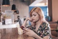 A young asian woman checks her inbox, seeing her boyfriend's alibi for being late, visibly annoying her.