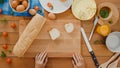 Young Asian woman chef spread butter on rustic rye bread with metal knife on wooden board on kitchen table in house. Fresh Royalty Free Stock Photo