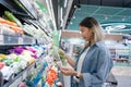 Young Asian woman chooses to buy organic vegetables on the shelves in the supermarket