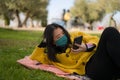Young Asian woman in city park during covid19 - happy and pretty Chinese girl in face mask using internet with mobile phone Royalty Free Stock Photo