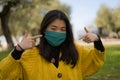 Young Asian woman in city park during covid19 - happy and pretty Korean girl in face mask standing on green grass during virus Royalty Free Stock Photo
