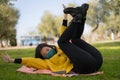 Young Asian woman in city park during covid19 - lifestyle portrait of happy and pretty Korean girl in face mask lying playful on Royalty Free Stock Photo