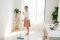 Young Asian woman cleaning floor at home doing chores with attractive smile on face Royalty Free Stock Photo