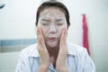 Young asian woman cleaning her face with facial foam in bathroom Royalty Free Stock Photo