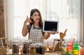 Young Asian woman cooking in the kitchen and holding digital tablet Royalty Free Stock Photo