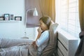 Young asian woman coughing and sitting on her bed after wake up