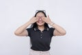 A young asian woman covers her eyes with her hands while smiling. Excited and anticipating a happy surprise.