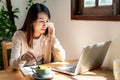 Young woman with cup of coffee using mobile phone and working on laptop at coffee shop Royalty Free Stock Photo