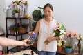 Young asian woman customer holding bouquet of flowers paying with credit card at flower shop Royalty Free Stock Photo