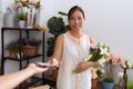 Young asian woman customer holding bouquet of flowers paying with dollars at flower shop Royalty Free Stock Photo