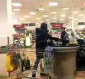 Woman shopper filling trolley inside major supermarket.
