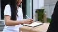 Young Asian woman customer signing on digital tablet and receiving package from delivery man. Royalty Free Stock Photo