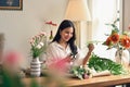Young Asian woman cutting flower stalk, arranging a vase with fresh flowers Royalty Free Stock Photo
