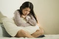 Young Asian woman depressed - young beautiful and sad Chinese girl on bed with pillow feeling unhappy and broken heart suffering