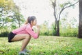 Young asian woman do squats for exercise to build up her beauty body in park environ with green trees.