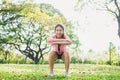 Young asian woman do squats for exercise to build up her beauty body in park environ with green trees.