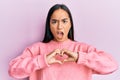 Young asian woman doing heart symbol with hands in shock face, looking skeptical and sarcastic, surprised with open mouth Royalty Free Stock Photo