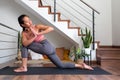 Young asian woman doing low lunge twist yoga pose at home. Parivrtta anjaneyasana home yoga practice.