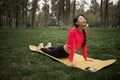 Young asian woman is doing yoga. Attractive woman in sports clothes lies on exercise mat in Cobra pose