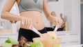 Young Asian woman drink orange juice making salad in the kitchen, beautiful female in sport clothing use organic fruits and Royalty Free Stock Photo