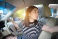 Young Asian woman driving car keeps wheel turning around looking back over shoulder check behind going reverse.