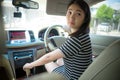 Young Asian woman driving car keeps wheel turning around looking back over shoulder check behind going reverse.
