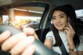 Young Asian woman driving car and talking on cell phone with smiling face on the road