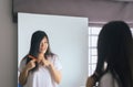 Young asian woman drying her long hair with dryer or comb front of mirror Royalty Free Stock Photo