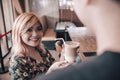 A young asian woman with dyed strawberry blonde hair raves about a delicious iced coffee to a waiter or barista. Royalty Free Stock Photo