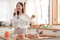 Young asian woman eat red and green apples with cheerful mood in the morning kitchen. Royalty Free Stock Photo