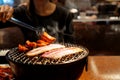 Young Asian woman eating BBQ in restaurant. Korean barbecue or Yakiniku in Japanese style. Closeup Royalty Free Stock Photo