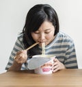 A young asian woman eating an instant noodles