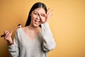 Young asian woman eating japanese food, holding salmon and rice maki sushi using chopsticks with happy face smiling doing ok sign Royalty Free Stock Photo