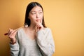 Young asian woman eating japanese food, holding salmon and rice maki sushi using chopsticks serious face thinking about question, Royalty Free Stock Photo