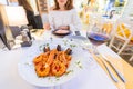 asian woman eating mediterranean seafood cuisine and drinking wine in restaurant