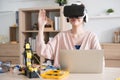 Young Asian woman engineer programer wear vr control learning robot arm ai coding programer working on robotics project at home.