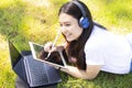 Young Asian woman is enjoy lifestyle with remotely working by using tablet and laptop, lay down on the green grass Royalty Free Stock Photo