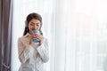 Young Asian woman enjoy listening to music with headphones and holding a hot cup of coffee, happy and relaxing time Royalty Free Stock Photo