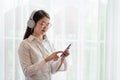 Young Asian woman enjoy listening to music with headphones while holding mobile phone, happy and relaxing time Royalty Free Stock Photo